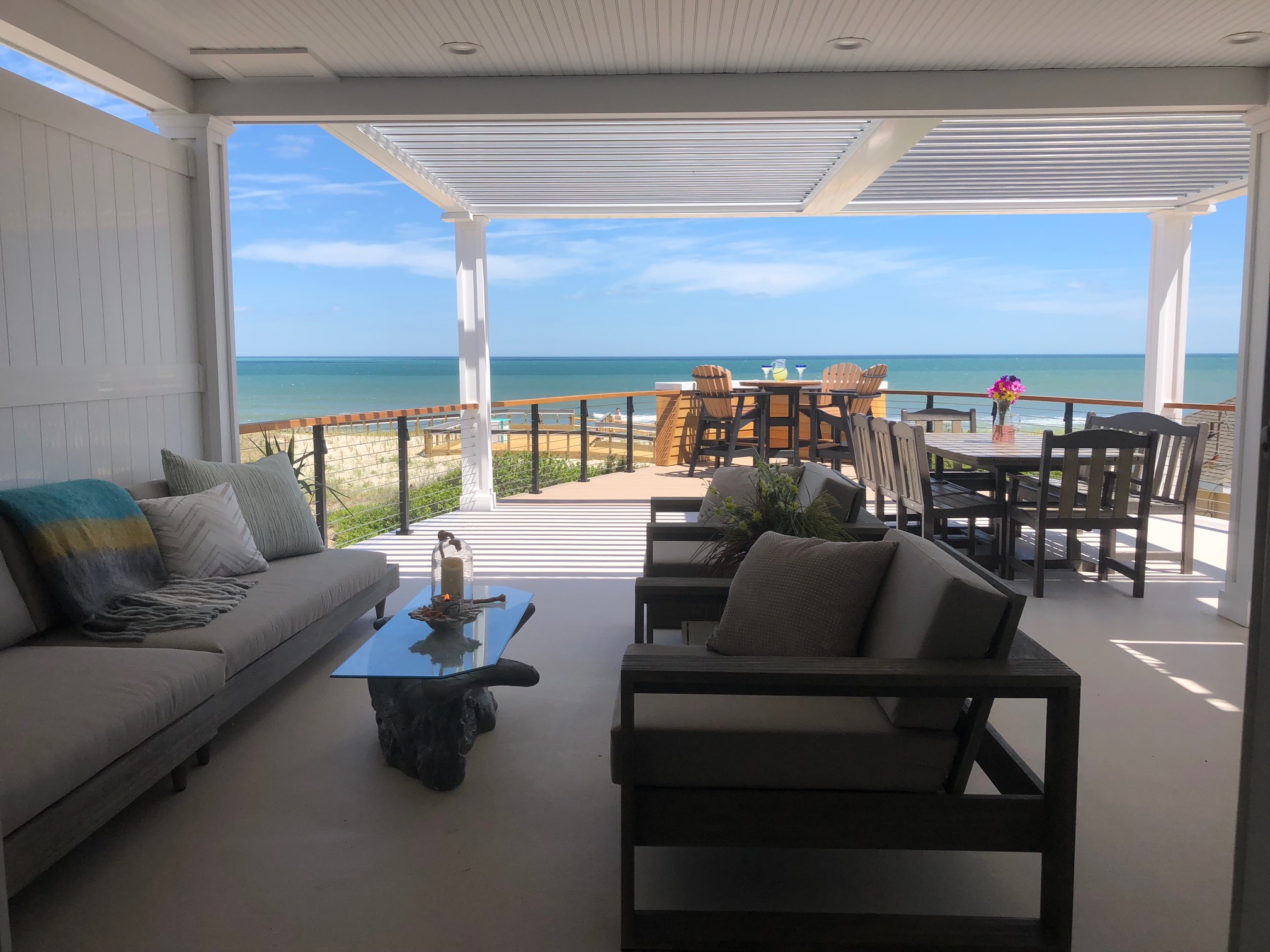White multi-bay Sundance louvered pergola with louvers open over an oceanfront patio