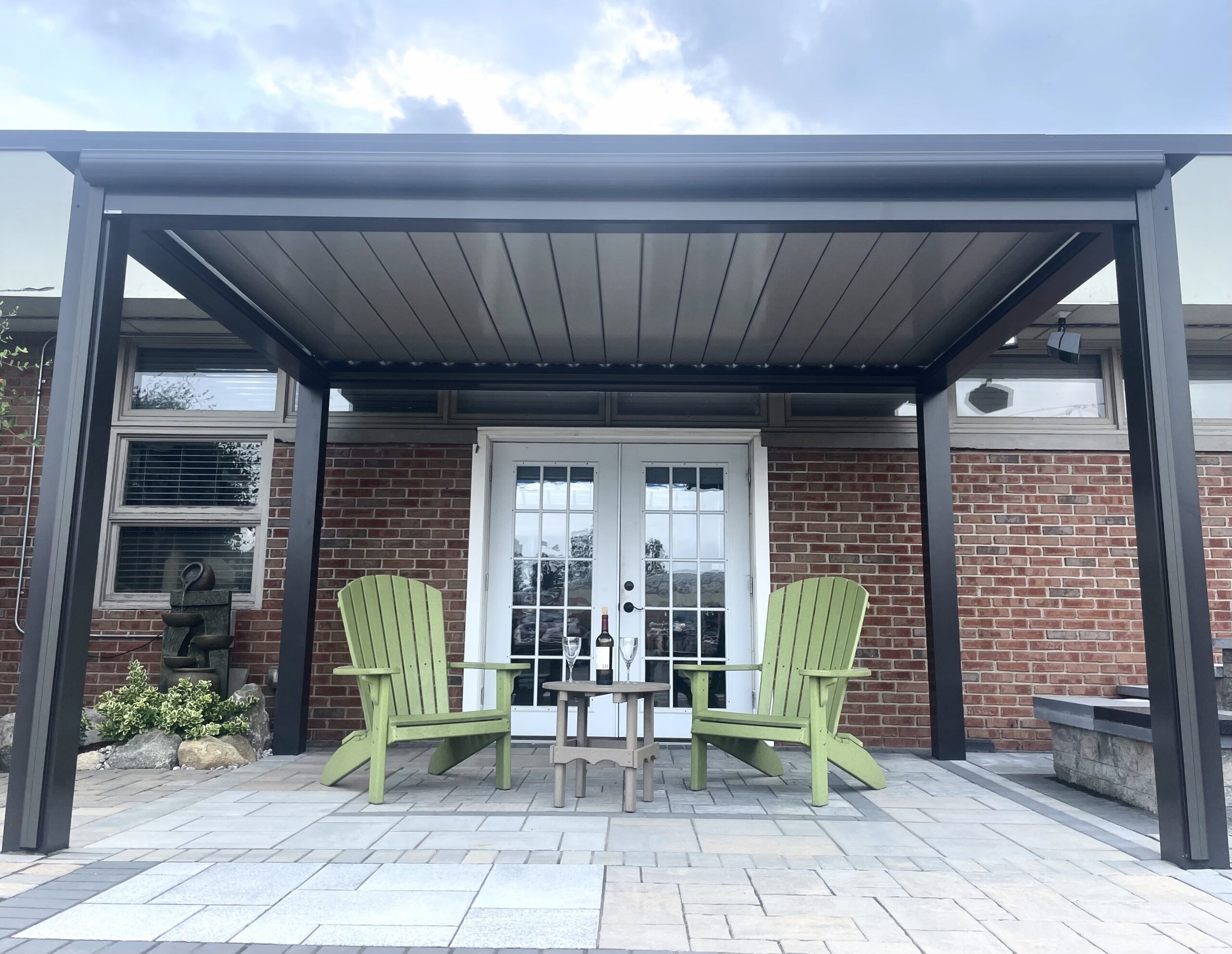 Black Sundance louvered pergola with tan louvers closed over a brick home patio
