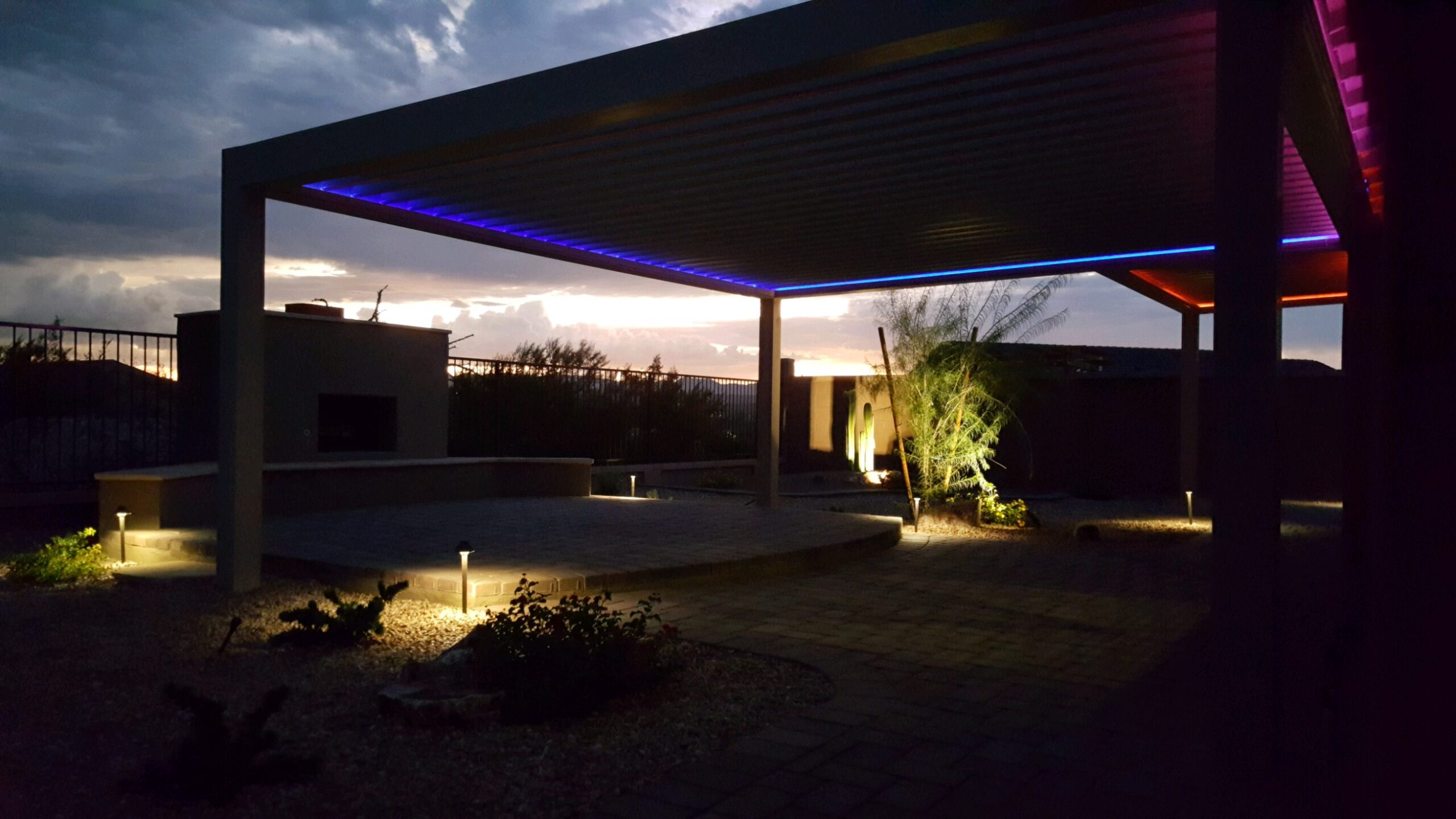Multi-bay Sundance louvered pergola with LED strip lighting glowing at sunset
