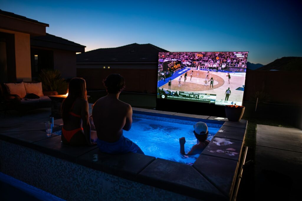 Large TV on an outdoor patio at dusk, showing a game