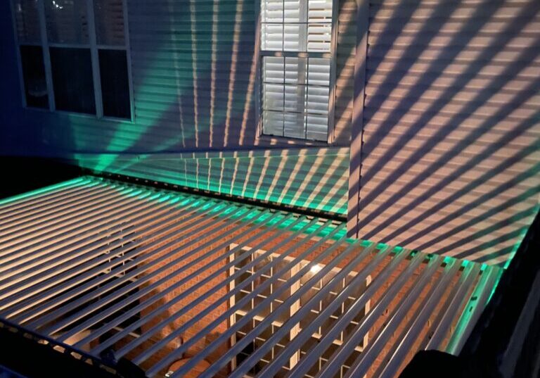 Two-bay bronze Sundance louvered pergola with white louvers and LED strip lighting